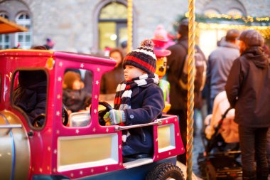 Komik küçük çocuk çocuk Noel lunapark veya Pazar, açık havada bir atlıkarınca üstünde. Mutlu çocuk eğleniyor. Almanya, Europe geleneksel Noel Pazar. Tatil, çocuklar, yaşam tarzı konsepti.
