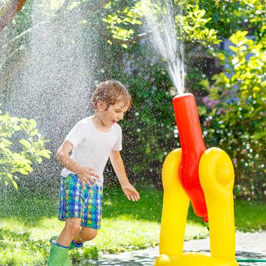 bir bahçe ile oynarken küçük çocuk çocuk hortum ve su