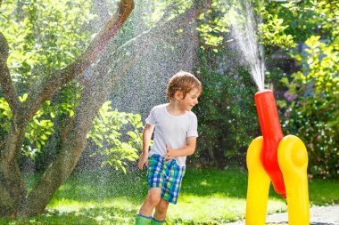 bir bahçe ile oynarken küçük çocuk çocuk hortum ve su