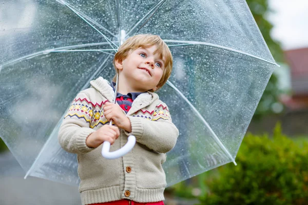 Liten blond liten pojke promenader med stora paraply utomhus — Stockfoto