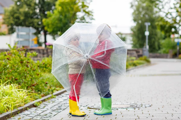 Dos niños pequeños con un gran paraguas al aire libre — Foto de Stock