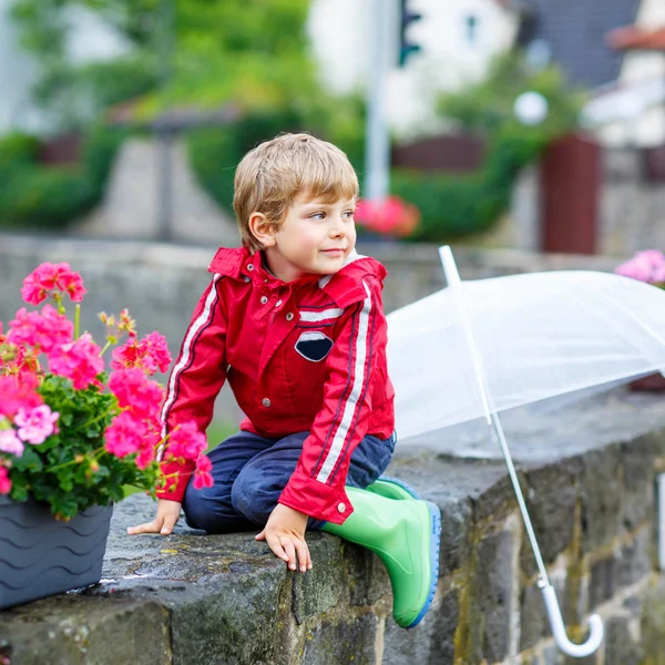 Little blond kid boy with big umbrella outdoors — Stockfoto