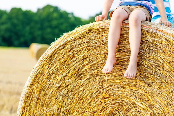 Kid jongetje zittend op baal hooi in de zomer — Stockfoto