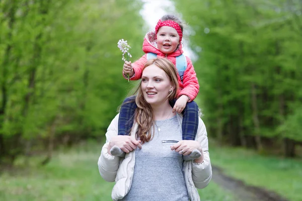 Beautiful mother carrying little girl on shoulders. — Stock Photo, Image