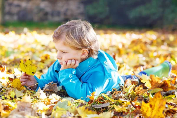 Liten unge pojke med gula hösten lämnar i park — Stockfoto