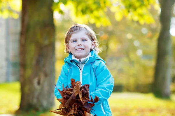 Liten gutt med gule høstblader i parken – stockfoto