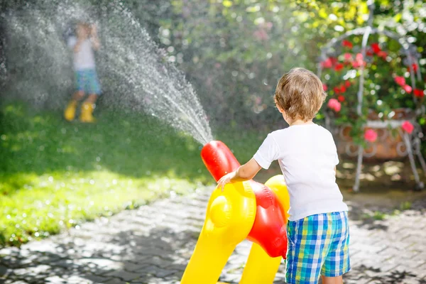 Duas crianças brincando com mangueira de jardim no verão — Fotografia de Stock