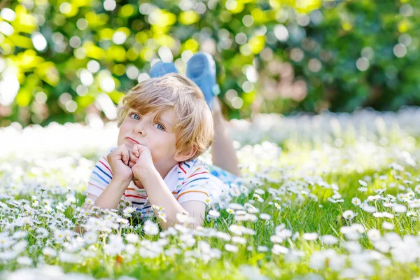 Happy kid boy laying on green grass in summer — Stock Photo, Image