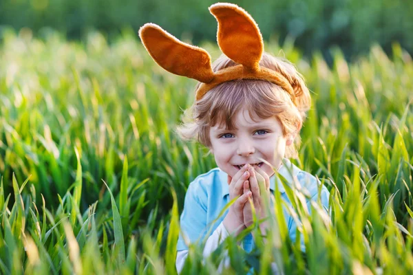 Pequeño niño con orejas de conejo de Pascua y comer chocolate en — Foto de Stock