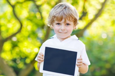 Preschool little boy with tablet pc, outdoors