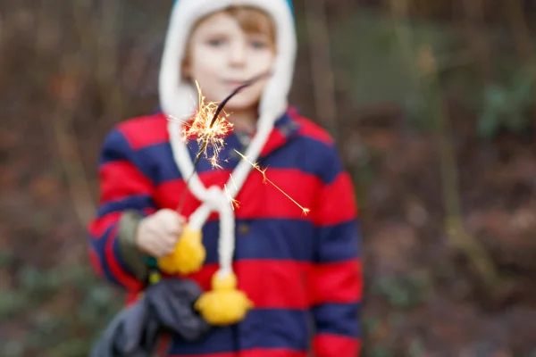 Criança pequena em roupas de inverno segurando brilho ardente — Fotografia de Stock