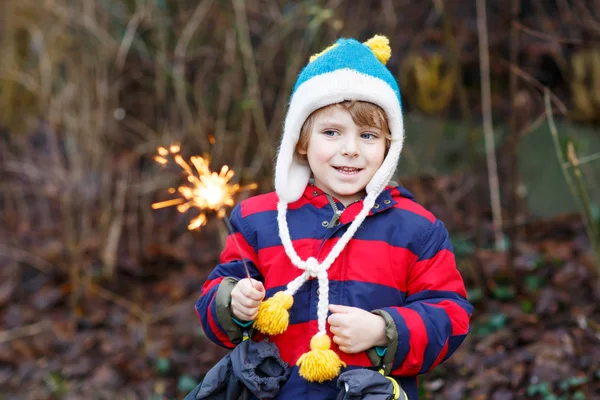 Criança pequena em roupas de inverno segurando brilho ardente — Fotografia de Stock