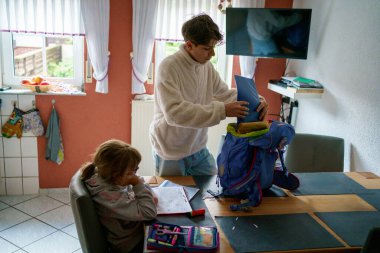 Küçük kız okul ödevini yapıyor. Not defterine yazan ve ders kitabı kullanan bir çocuk. Genç kardeş zor işlerde yardımcı olur..