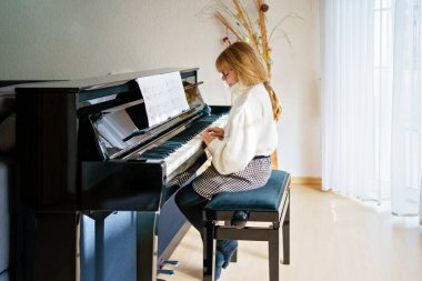 Evde piyano çalan küçük bir kız. Mutlu çocuk müzik aleti çalıyor..