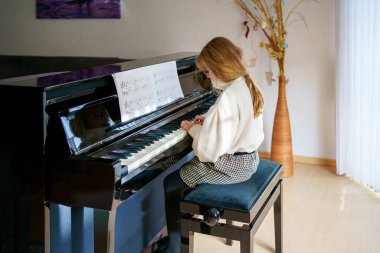 Evde piyano çalan küçük bir kız. Mutlu çocuk müzik aleti çalıyor..