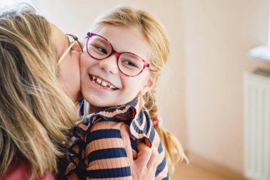 Küçük kızını kucaklayan mutlu bir anne. Sevimli mutlu okul çocuğu ve kadın.
