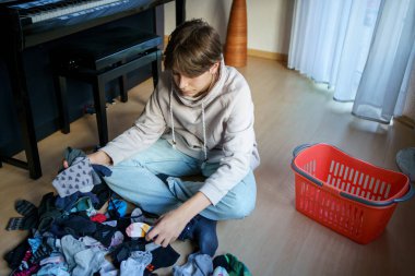 Yıkandıktan ve çamaşır yıkadıktan sonra çorapları sıralayan genç çocuk..