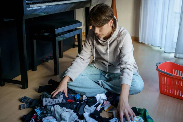 Yıkandıktan ve çamaşır yıkadıktan sonra çorapları sıralayan genç çocuk..