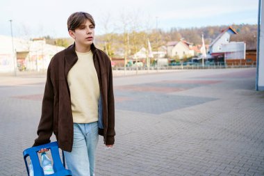 Ergen çocuk alışveriş yapmak ve maden suyu kutularını değiştirmek için markete gidiyor.