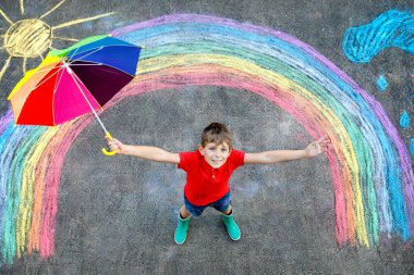 Lastik çizmeli, gökkuşağı güneşli, yağmur damlalı bulutlu renkli tebeşirle boyanmış mutlu çocuk yaz mevsiminde. Yazın dışarıda çocuklar için yaratıcı bir eğlence..