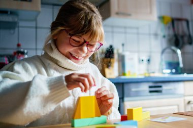 Evde tahta bloklar oynayan küçük bir kız.