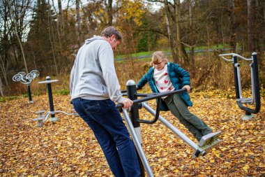 Küçük kız ve babası dışarıda çeşitli spor malzemeleriyle jimnastik yapıyor..