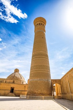 Buhara, Özbekistan 'daki Kalyan Minaresi, tarihi şehrin üzerinde mavi gökyüzünün altında yükselen devasa İslami mimari kulesi.