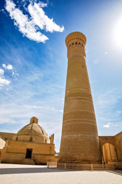 Buhara, Özbekistan 'daki Kalyan Minaresi, tarihi şehrin üzerinde mavi gökyüzünün altında yükselen devasa İslami mimari kulesi.