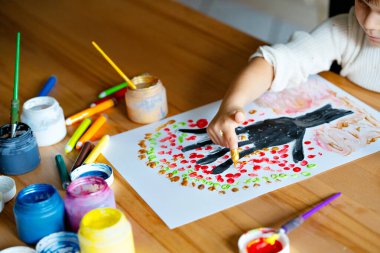 Anaokulundaki küçük kız evde ya da kreşte parmakları kağıt üzerinde resim yapıyor. İçeride yaratıcı sanat aktiviteleri yapan bir çocuk. Gerçek hayat, gerçek insanlar.