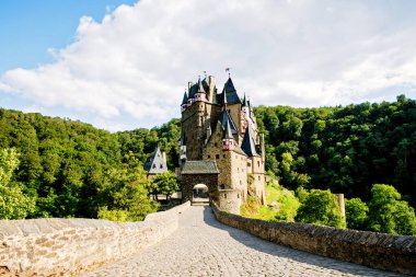 Muhteşem ortaçağ Eltz Şatosu yaz güneşinde yemyeşil ormanlarla çevrili. Kuleleri ve taş duvarları olan tarihi mimari, Almanya 'nın en güzel simgelerinden biri..