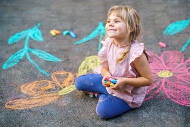 Yürümeye başlayan kız, kaldırım tebeşiri ile renkli çiçekler çiziyor, kaldırımda yaratıcı bir oyun oynuyor, tasasız bir çocukluk geçiriyor, gerçek insanlar.