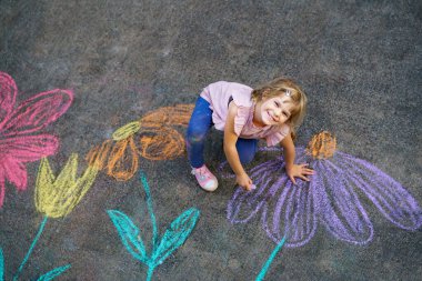 Yürümeye başlayan kız, kaldırım tebeşiri ile renkli çiçekler çiziyor, kaldırımda yaratıcı bir oyun oynuyor, tasasız bir çocukluk geçiriyor, gerçek insanlar.