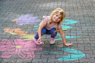 Yürümeye başlayan kız, kaldırım tebeşiri ile renkli çiçekler çiziyor, kaldırımda yaratıcı bir oyun oynuyor, tasasız bir çocukluk geçiriyor, gerçek insanlar.