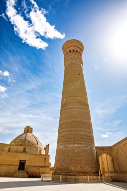Buhara, Özbekistan 'daki Kalyan Minaresi, tarihi şehrin üzerinde mavi gökyüzünün altında yükselen devasa İslami mimari kulesi.