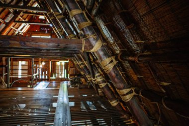 Shirakawa-go 'daki geleneksel go-zukuri çiftlik evinin içinde, ahşap kirişler, sazdan çatı yapısı ve tarihi işçilik gösteriliyor..