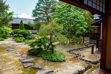 Taş yolları, budanmış ağaçları ve ahşap binaları olan geleneksel Japon bahçesi tarihi bir evden görünen huzurlu bir yaz bahçesi..