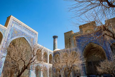 Semerkand, Özbekistan 'daki Registan Meydanı' nın bir parçası, parlak mavi gökyüzü altında karmaşık mozaik tasarımlar, kubbeler ve minareler içeren üç çarpıcı medresenin yer aldığı tarihi bir mimari grup..