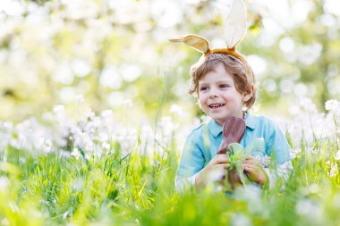 Paskalya bunny kulaklar giyen ve yeme çikolata s küçük çocuk