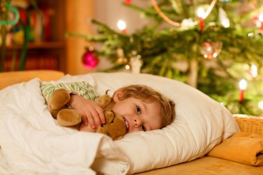 Küçük şirin sarışın çocuk Noel ağacının altında uyku