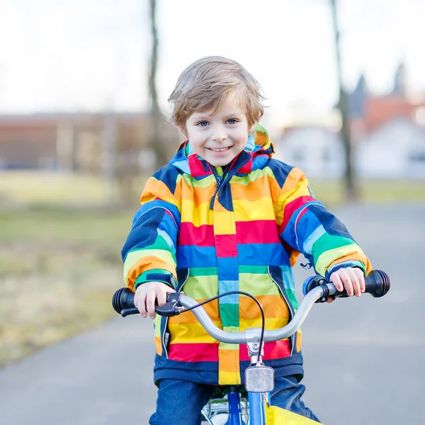 Enfant en casque de sécurité et imperméable coloré vélo d'équitation, outd — Photo