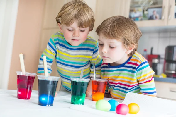 Två små blonda barn pojkar färgning ägg till påsk — Stockfoto