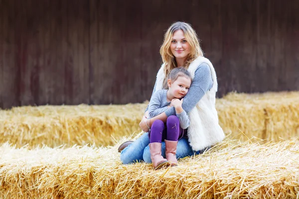 Glad tjej och mamma att ha kul med hö på en gård — Stockfoto