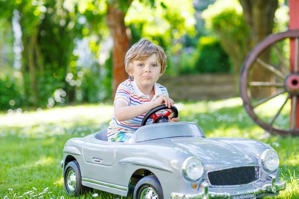 Ragazzo che guida con grande auto giocattolo all'aperto — Foto Stock