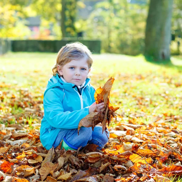 Menino com folhas de outono amarelas no parque — Fotografia de Stock