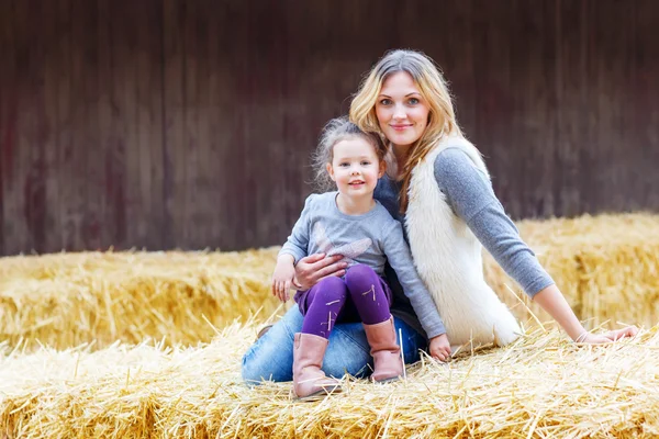 Happy girl and mother having fun with hay on a farm — Stock Photo, Image