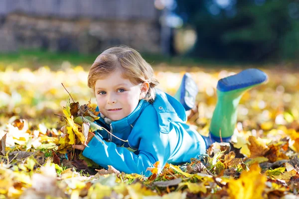 Liten unge pojke med gula hösten lämnar i park — Stockfoto