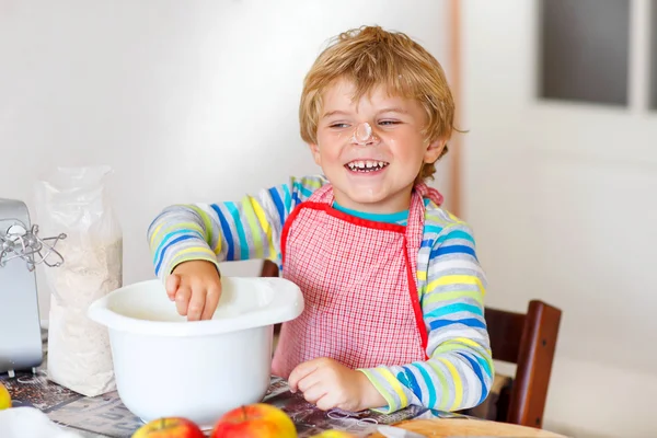 Divertido chico rubio hornear pastel de manzana en el interior — Foto de Stock