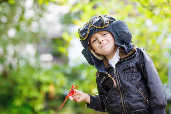 Little kid boy in pilot helmet playing with toy airplane — Stock Photo, Image