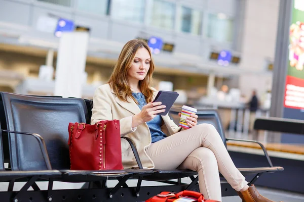 Kobieta na międzynarodowym lotnisku, czytając ebooka i pijąc kawę — Zdjęcie stockowe