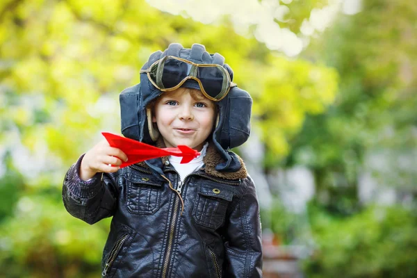 Kleiner Junge im Pilotenhelm spielt mit Spielzeugflugzeug — Stockfoto